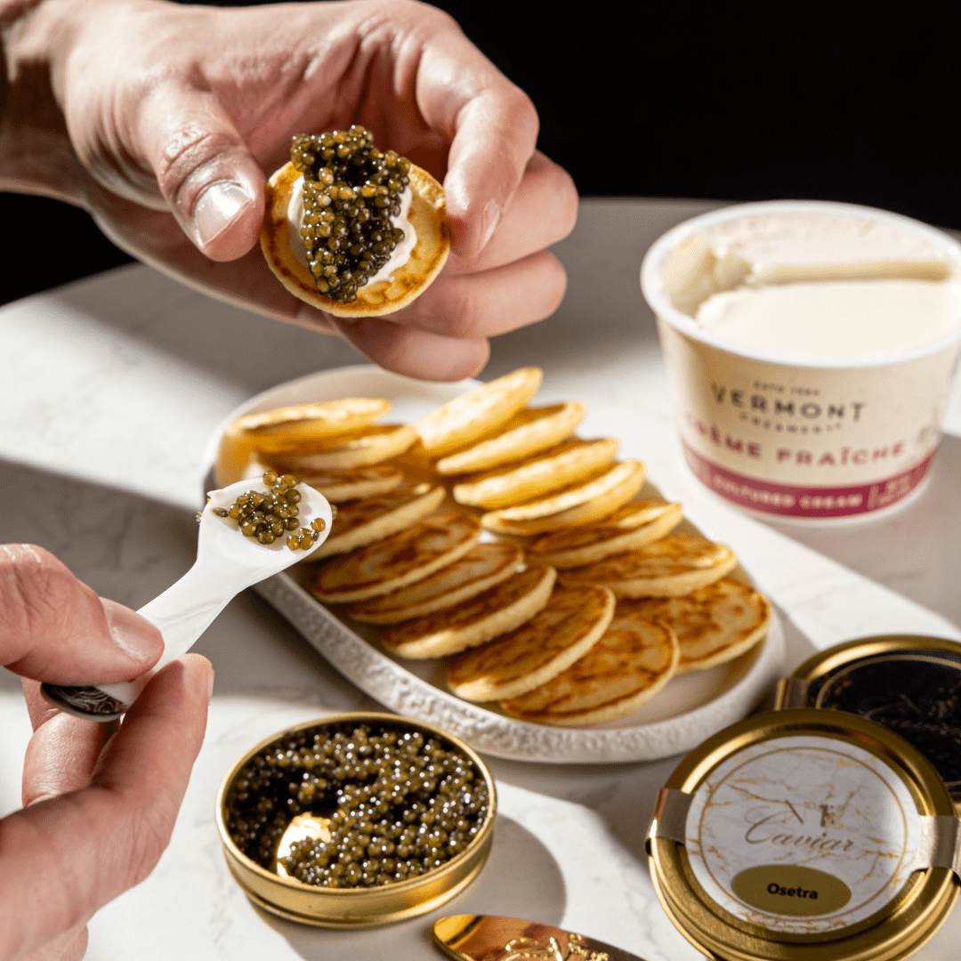Caviar being served on crackers with a bowl of creme fraiche in the background.