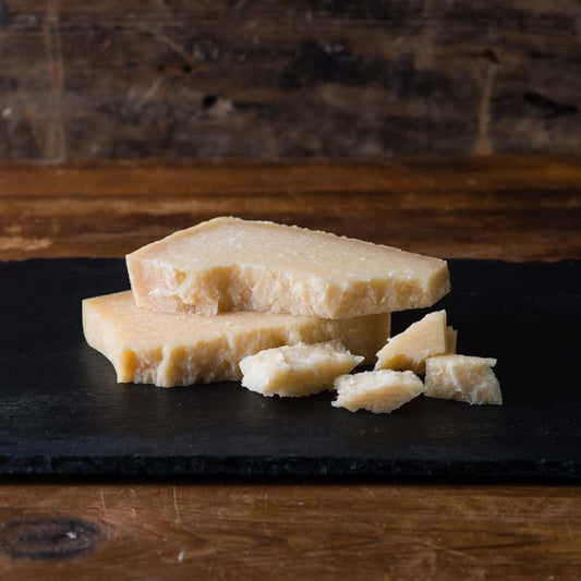 Slices of cheese on a black slate board with a wooden background