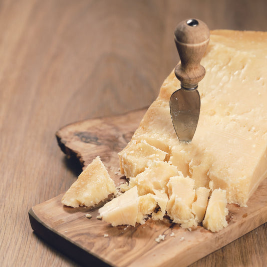 Block of Parmesan cheese with a knife on a wooden board