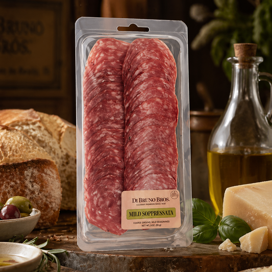 Packaged salami with Di Bruno Bros branding on a rustic wooden table with bread and olive oil.
