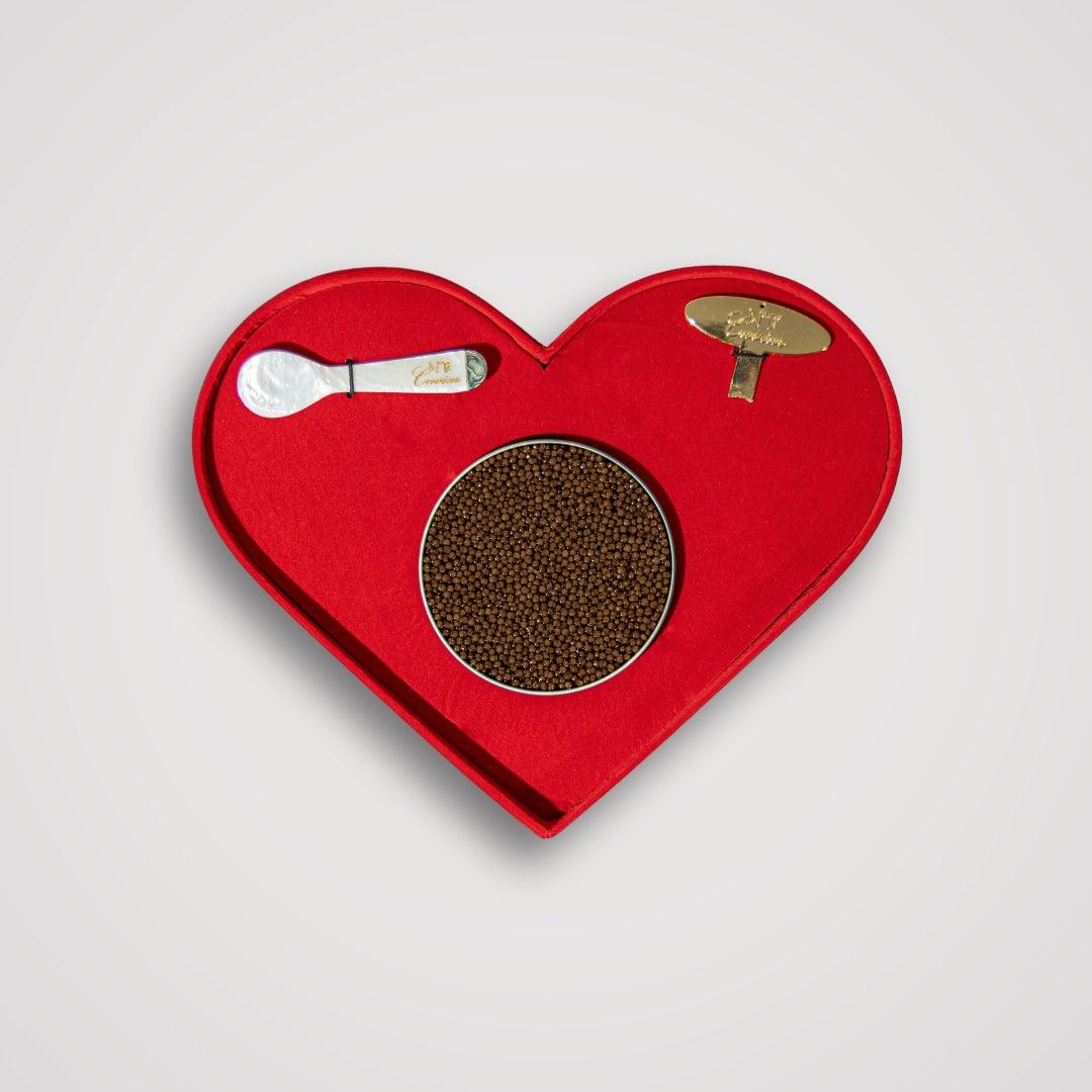 Red heart-shaped tray with a brown circular item and silver utensils on a light gray background